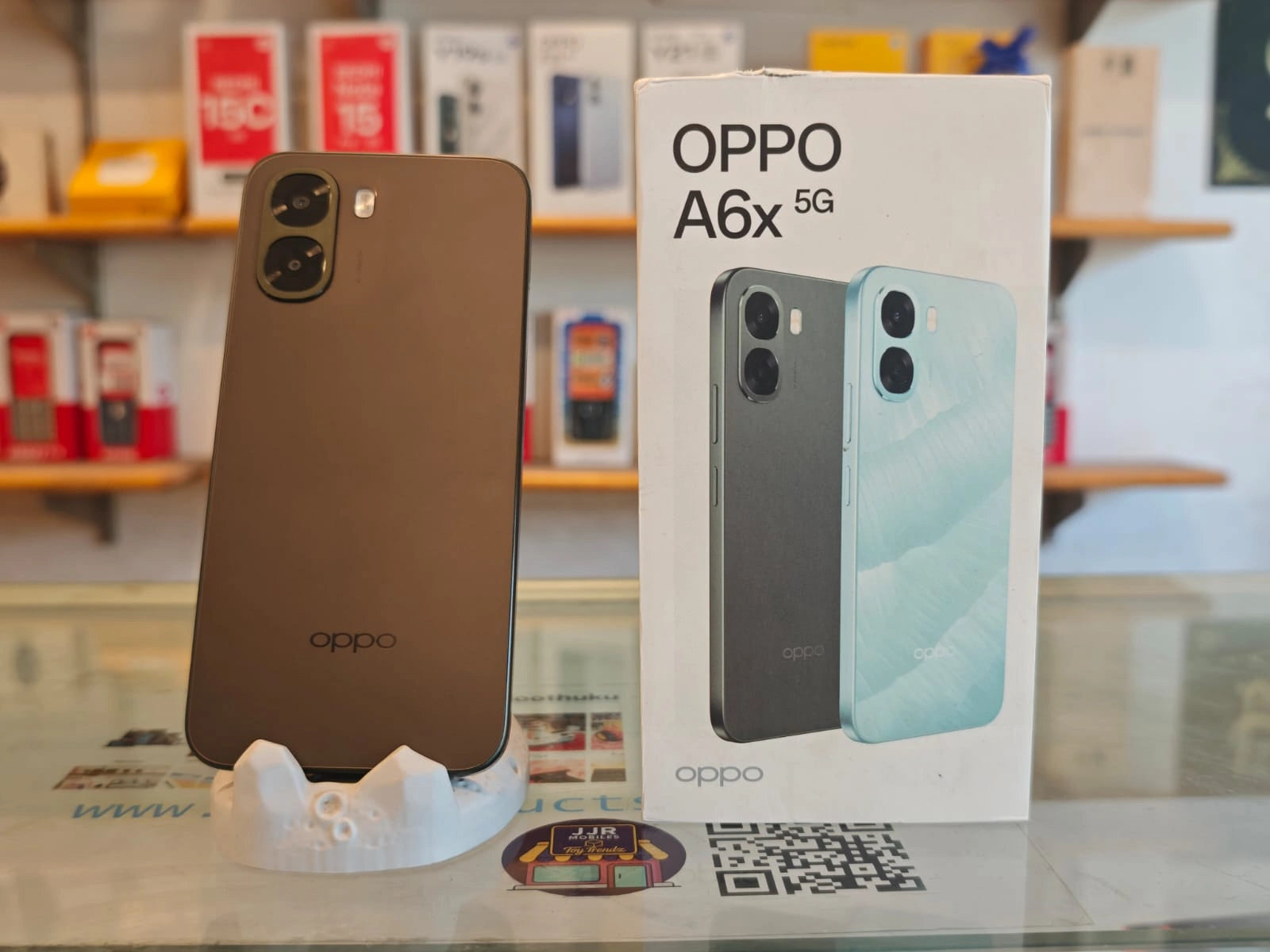 OPPO A6x 5G smartphone in brown finish displayed beside retail box showcasing stylish design, dual AI camera setup, and 5G connectivity.