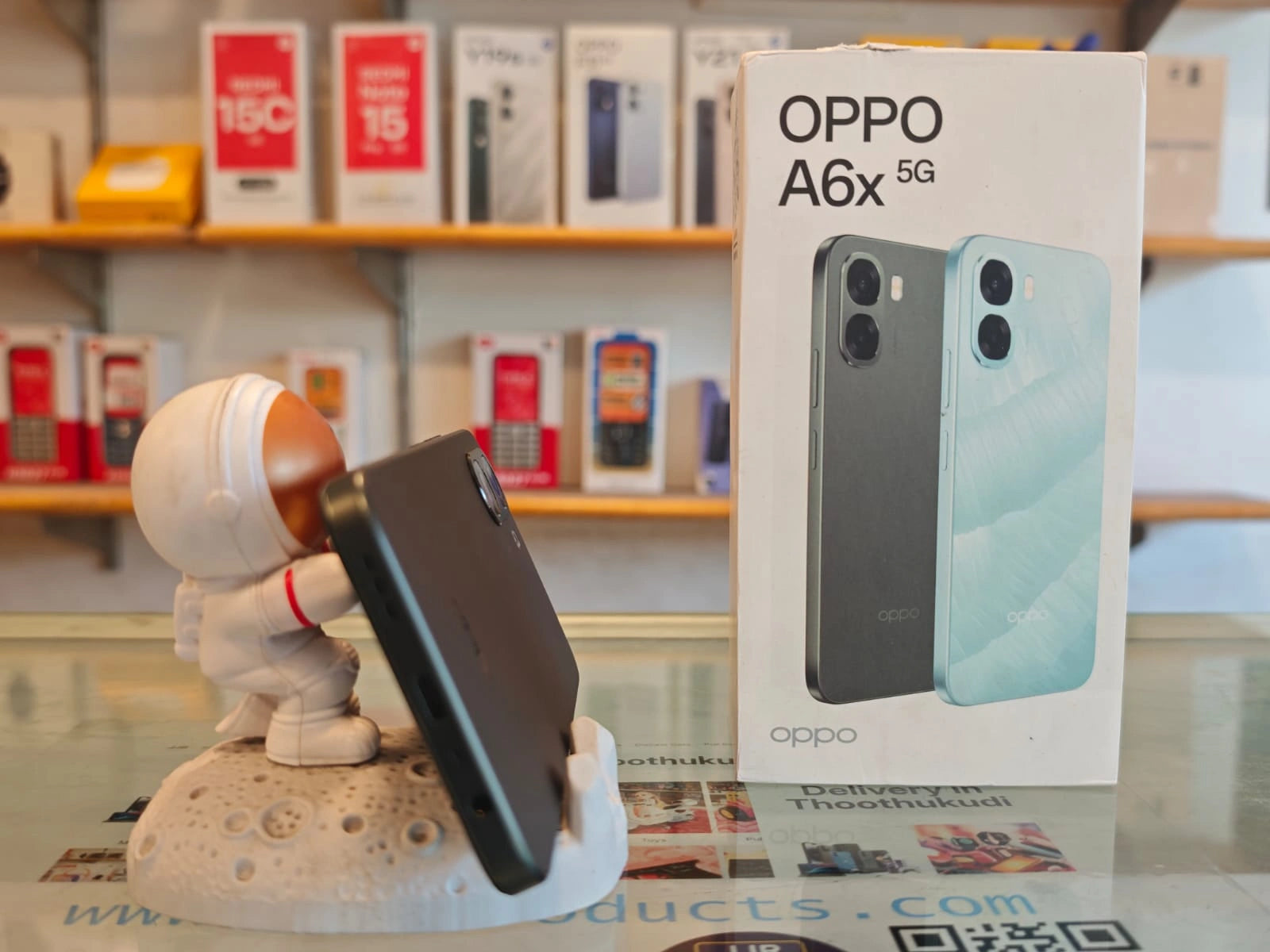 OPPO A6x 5G smartphone in brown finish displayed beside retail box showcasing stylish design, dual AI camera setup, and 5G connectivity.